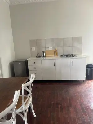 a kitchen with white cabinets and a table and chairs at Lani Accommodation in Pretoria