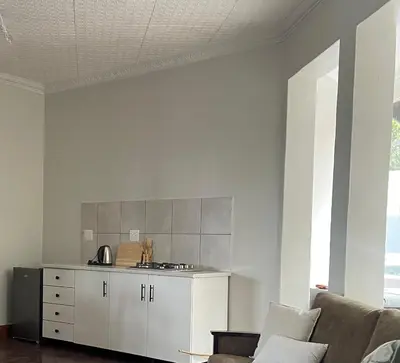 a living room with a couch and a kitchen at Lani Accommodation in Pretoria