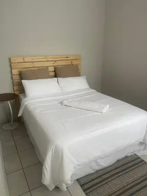 a large white bed with a white blanket on it at Lani Accommodation in Pretoria