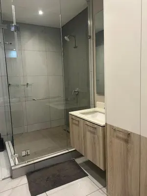 a bathroom with a glass shower and a sink at Luxury 7th Floor Menlyn Maine Residences in Pretoria