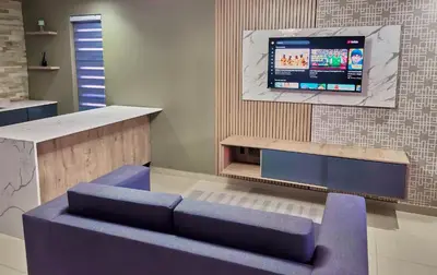 a living room with a blue couch and a tv at Pereng Lodge in Ga-Moloi