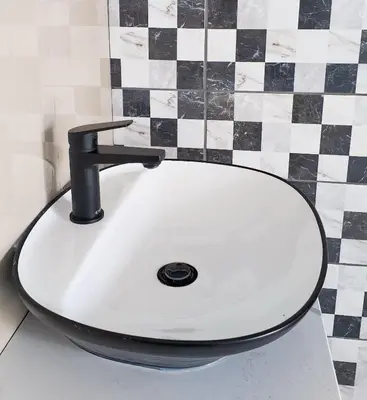 a white sink with a black faucet in a bathroom at Pereng Lodge in Ga-Moloi
