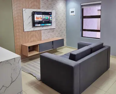 a living room with a couch and a tv on a wall at Pereng Lodge in Ga-Moloi