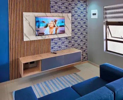 a living room with a blue couch and a tv at Pereng Lodge in Ga-Moloi
