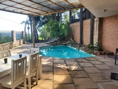 a swimming pool in a patio with two chairs at Sunset Cottage - Own Water - Own Electricity in Pretoria