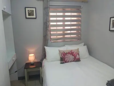 a bedroom with a white bed with a lamp on a table at Sunset Cottage - Own Water - Own Electricity in Pretoria