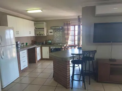 a kitchen with a bar with stools and a tv at Sunset Cottage - Own Water - Own Electricity in Pretoria