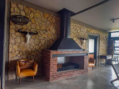a stone wall with a fireplace in a living room at vanDijksRus Farm in The Waterberg Biosphere