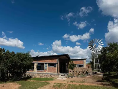 a farm building with a windmill in the background at vanDijksRus Farm in The Waterberg Biosphere
