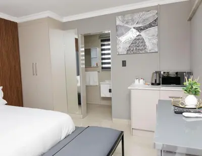 a white bedroom with a bed and a kitchen at Marikana guest house