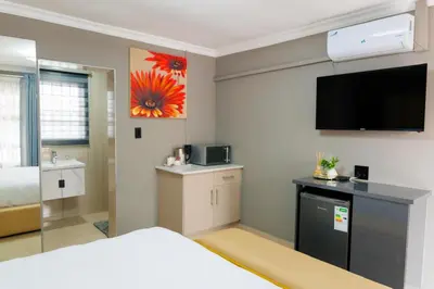 a hotel room with a bed and a flat screen tv at Marikana guest house