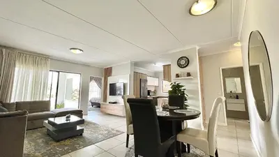 a living room with a dining table and a living room at The Blyde - Lagoon Facing 3 Bedroom apartment in Pretoria