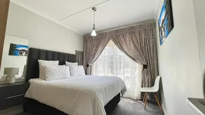 a bedroom with a bed and a large window at The Blyde - Lagoon Facing 3 Bedroom apartment in Pretoria