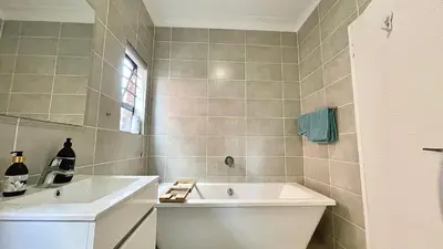 a bathroom with a sink and a bath tub at The Blyde - Lagoon Facing 3 Bedroom apartment in Pretoria