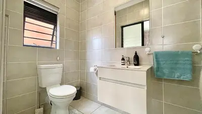a bathroom with a toilet and a sink and a mirror at The Blyde - Lagoon Facing 3 Bedroom apartment in Pretoria