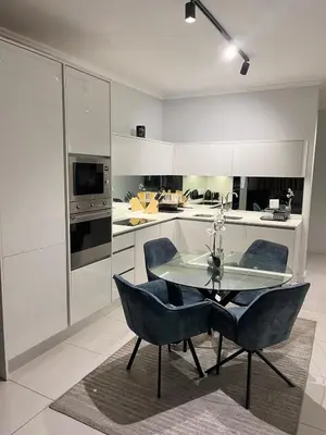 a kitchen with a glass table and two blue chairs at Mphoentle Residence ellipse waterfall in Midrand