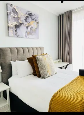 a bedroom with a large bed with a yellow blanket at Mphoentle Residence ellipse waterfall in Midrand