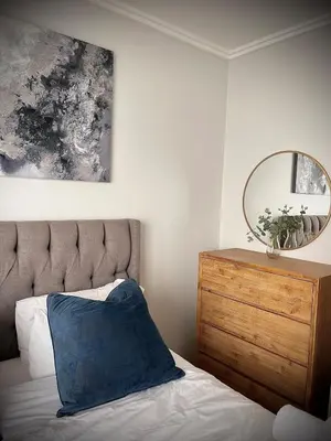 a bed with a blue pillow and a mirror at Mphoentle Residence ellipse waterfall in Midrand
