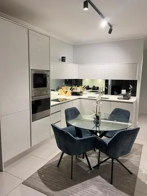 a kitchen with a glass table and two blue chairs at Mphoentle Residence ellipse waterfall in Midrand