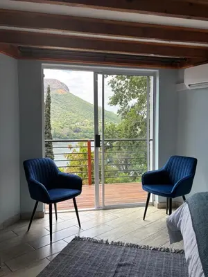 two blue chairs in a bedroom with a large window at The Manzi Villa in Hartbeespoort