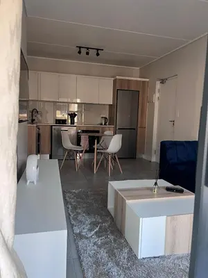 a living room and kitchen with a table and chairs at Crystal ace lagoon in Midrand