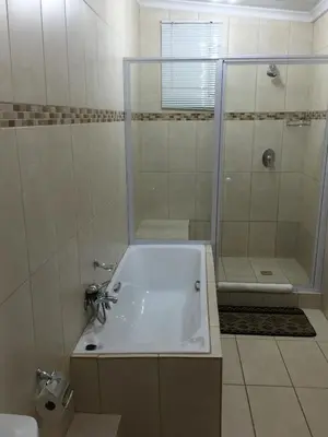 a bathroom with a tub and a shower and a sink at JC Studios Ermelo in Ermelo