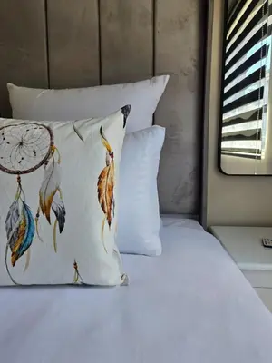 a bed with a pillow with feathers on it at Nat's Villa in Midrand