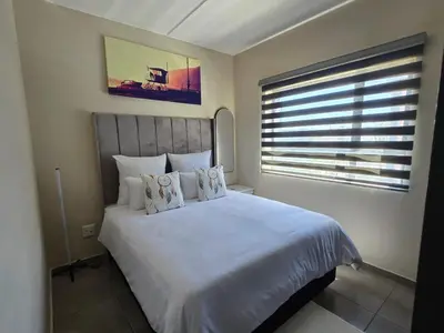 a bedroom with a large white bed with a window at Nat's Villa in Midrand