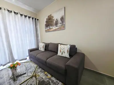 a living room with a couch and a glass table at Nat's Villa in Midrand