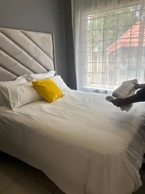 a white bed with yellow pillows and a window at Ruros Guest House in Kempton Park