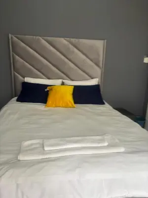 a white bed with a yellow pillow on it at Ruros Guest House in Kempton Park
