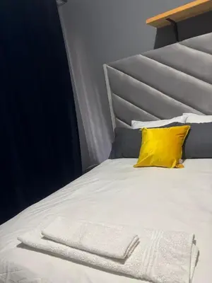 a white bed with a yellow pillow on it at Ruros Guest House in Kempton Park