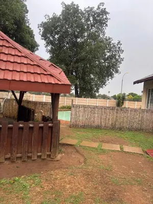 a wooden building with a red roof next to a fence at Ruros Guest House in Kempton Park