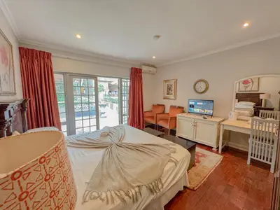 a bedroom with a bed and a desk and a television at Amoris Guesthouse - Waterkloof ridge in Pretoria