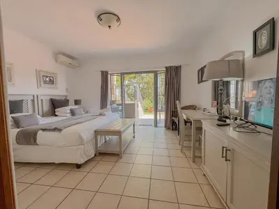 a hotel room with a bed and a desk and a desk at Amoris Guesthouse - Waterkloof ridge in Pretoria