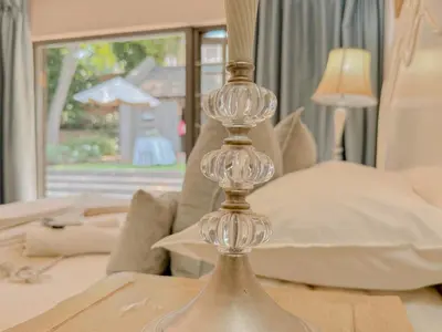 a glass candleholder on a table in front of a bed at Amoris Guesthouse - Waterkloof ridge in Pretoria