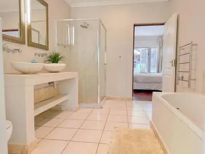 a bathroom with two sinks and a tub and a shower at Amoris Guesthouse - Waterkloof ridge in Pretoria