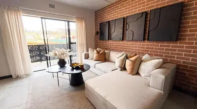 a living room with a couch and a brick wall at Elegant stay in Midrand