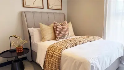 a bedroom with a bed with white sheets and pillows at Elegant stay in Midrand