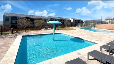 a swimming pool with an umbrella in front of a building at Elegant stay in Midrand
