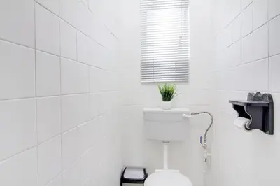 a white bathroom with a toilet with a plant on it at Spacious Valkyrie One-bedroom in Centurion