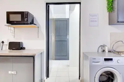 a kitchen with a washing machine and a microwave at Spacious Valkyrie One-bedroom in Centurion