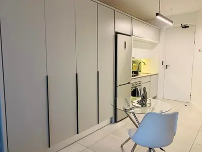 a kitchen with a glass table and a blue chair at Luxury Studio Apartment in Northdene