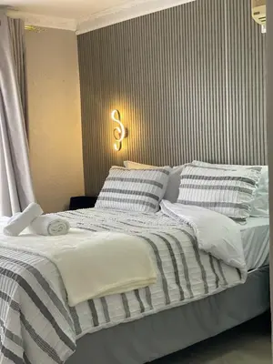 a bedroom with a bed with striped blankets and pillows at Nono's Boutique Guesthouse in Hectorspruit