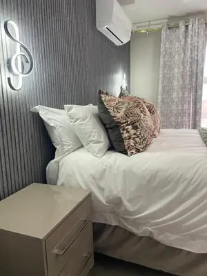 a bedroom with a large bed with white sheets and pillows at Nono's Boutique Guesthouse in Hectorspruit