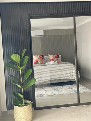 a mirror in a bedroom with a bed and a plant at Nono's Boutique Guesthouse in Hectorspruit