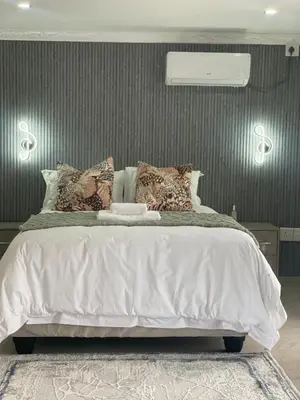 a bedroom with a large bed with white sheets and pillows at Nono's Boutique Guesthouse in Hectorspruit