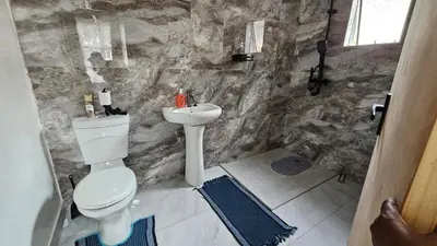 a stone bathroom with a toilet and a sink at Jacaranda Escape in Pretoria