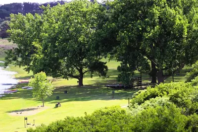 a park with trees and a playground next to the water at Jonatan at Genesaret in Lake Chrissie
