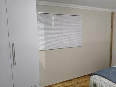 a white bedroom with a window and a bed at The Man Cave Extension in Sabie